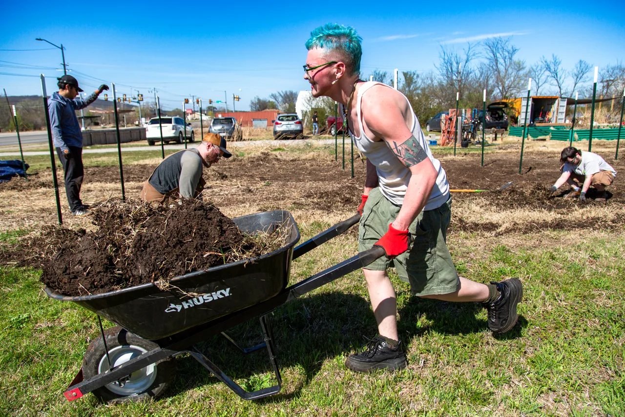 Volunteers moving soil by wheelbarrow at Flat Rock work day