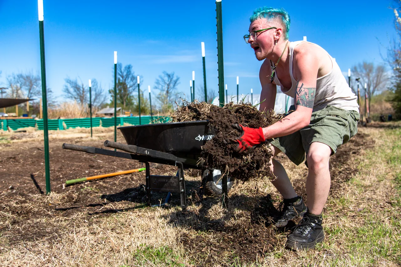 Volunteer loading wheelbarrow with compost at Flat Rock
